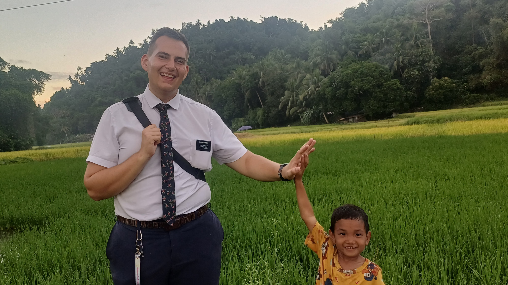 Elijah high-fiving a child in a rice field in the Philippines