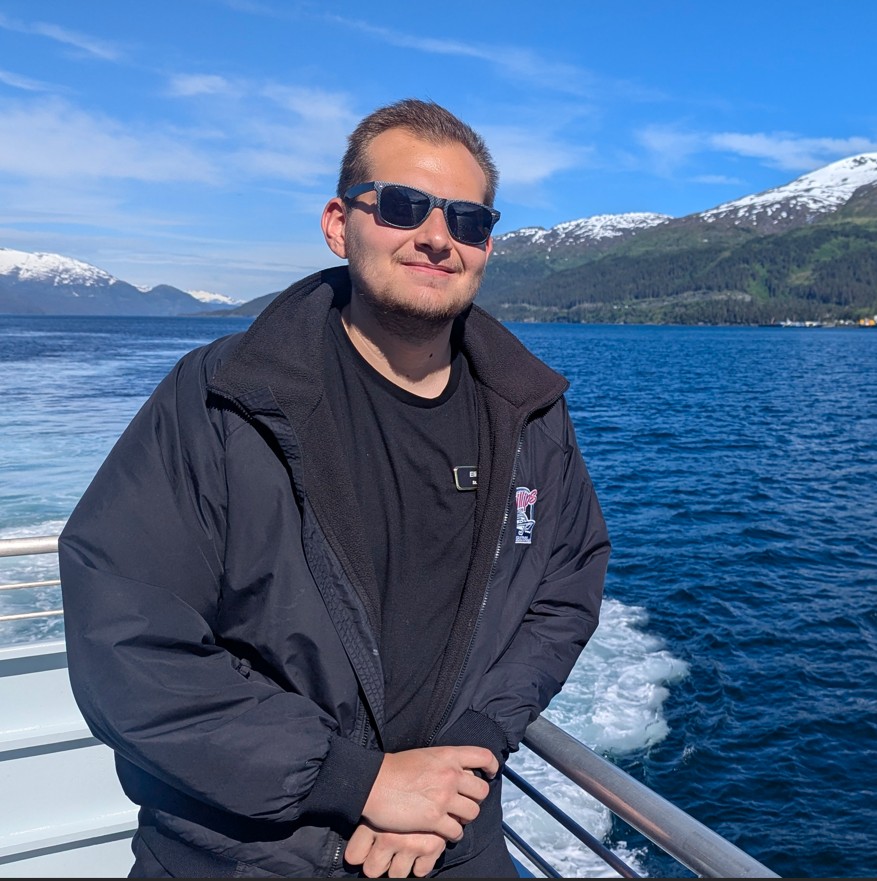 Elijah on a boat with mountains and harbor in the background